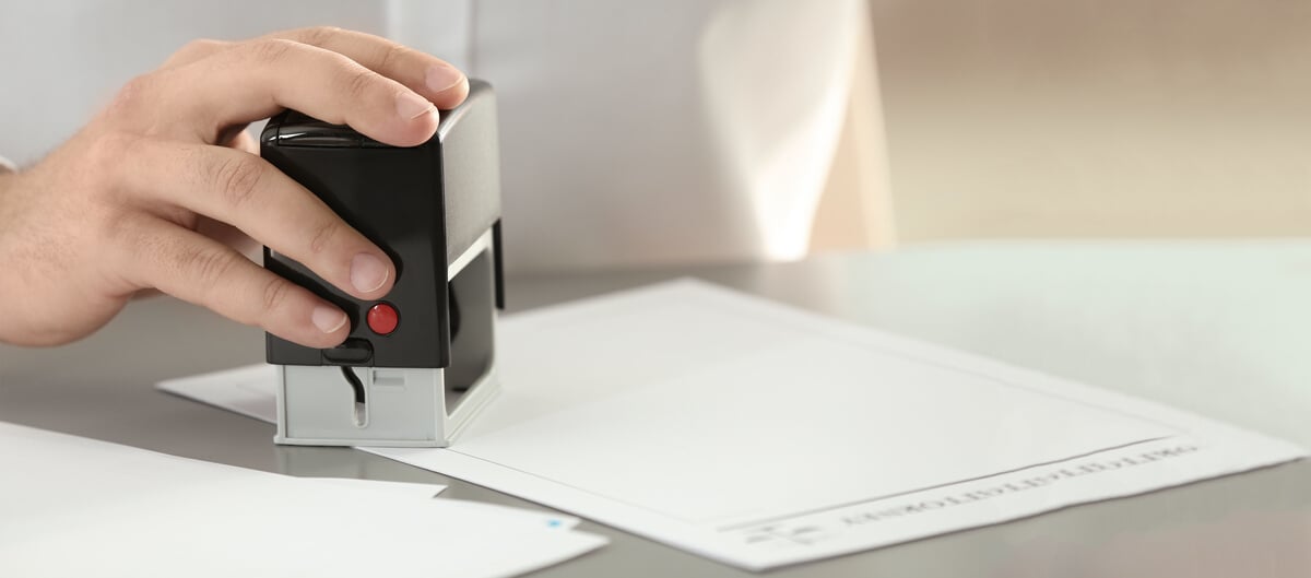Male Notary Stamping Document at Table, Closeup